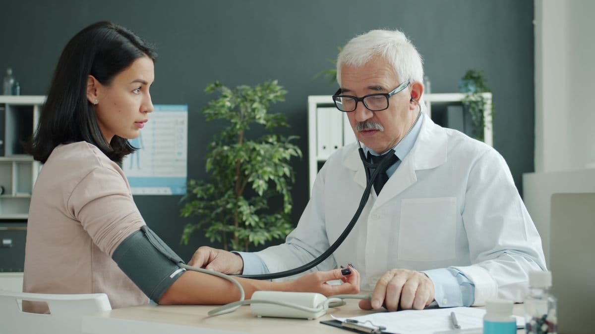 Doctor checking blood pressure of patient at medical clinic.