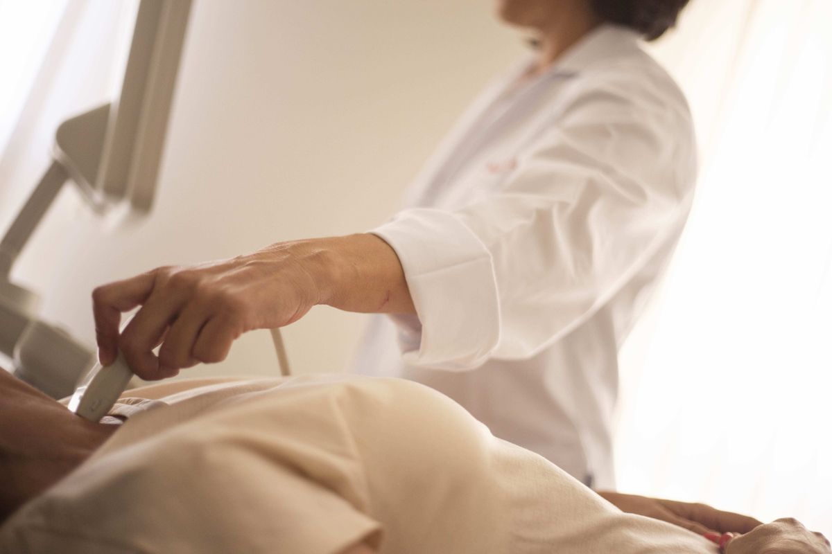 A medical professional conducts an ultrasound on a patient in a clinical setting.