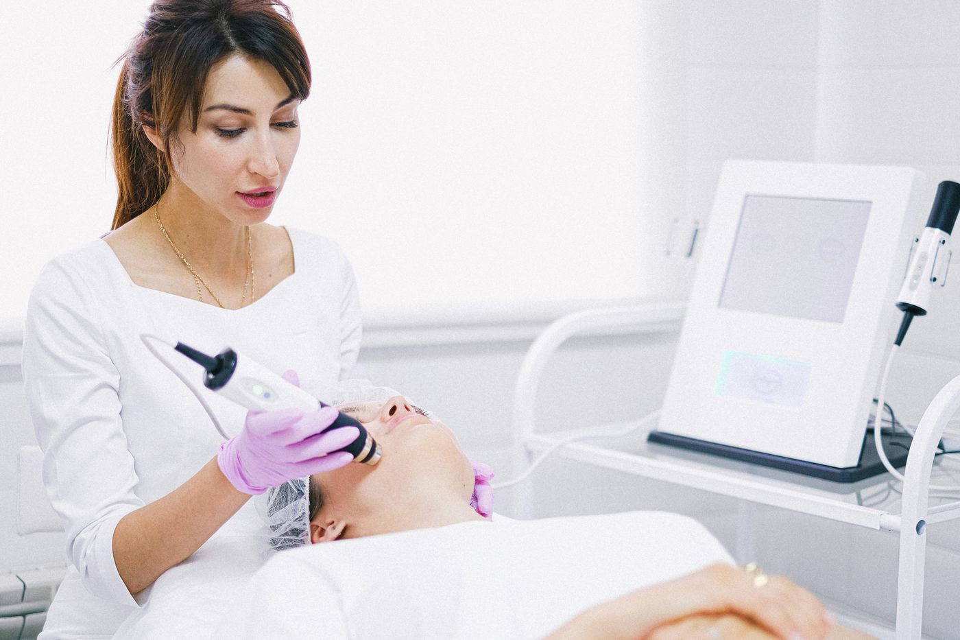Provider treating a patient’s face with a handheld resurfacing device